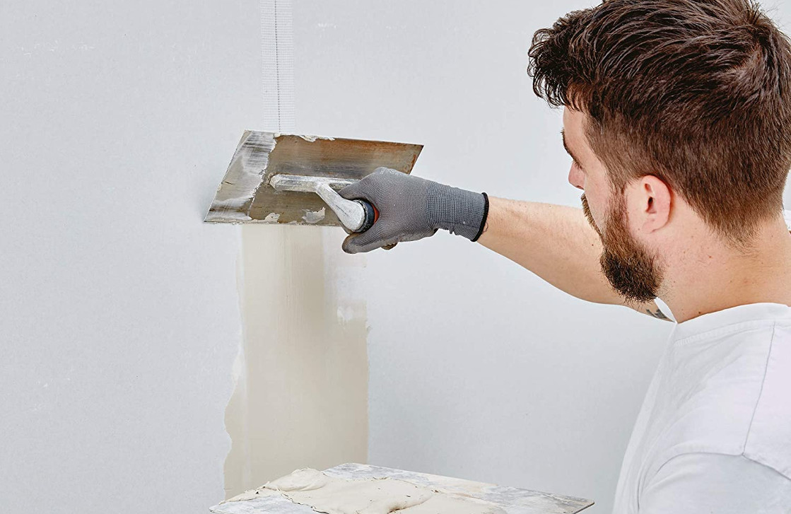 man applying joint compound to a plasterboard wall